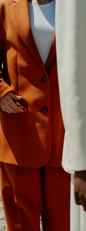 A bright orange suit behind a white suit