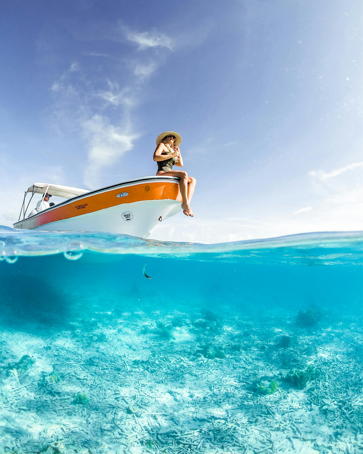 A woman sitting on the edge of a boat floating in the sea